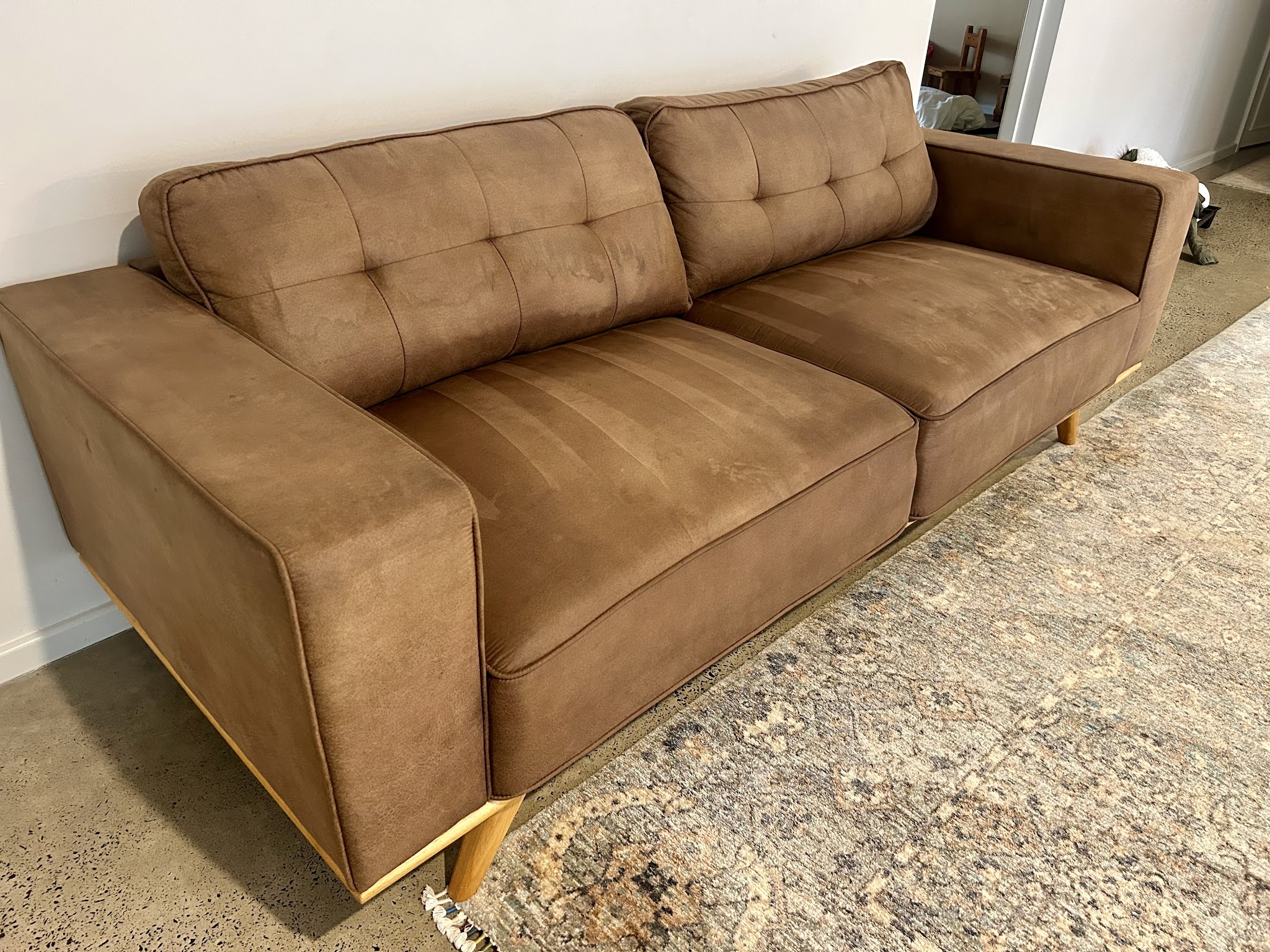 A tan fabric lounge with fresh cleaning marks across the seat cushions