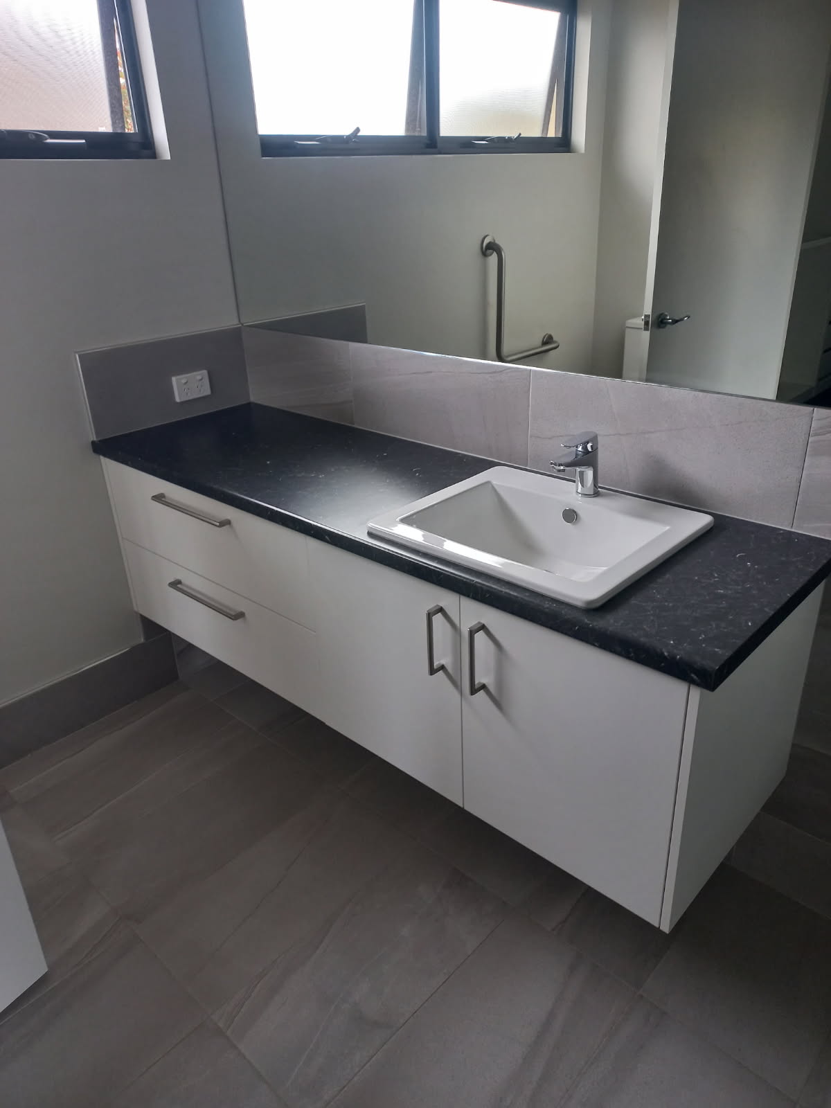 A cleaned bathroom vanity and grey tiled floor